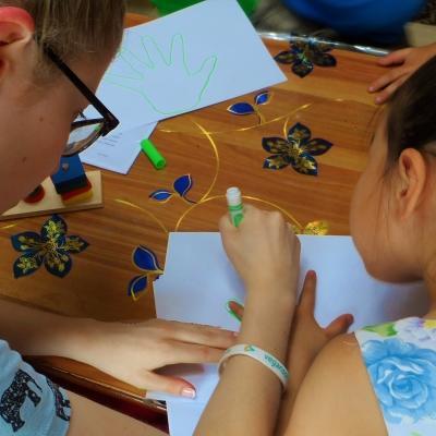 A female volunteer helps a child draw around their hands with a pen to increase motor skills at a Childcare Project in Mongolia. Projects Abroad volunteer working with children in Mongolia helps a child draw around their hands during an educational acitivity.